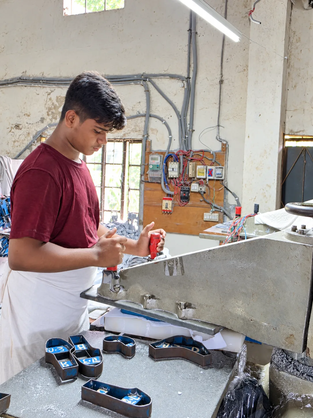 FD workshop team member preparing leather at a cutting press in a client-supplied photograph